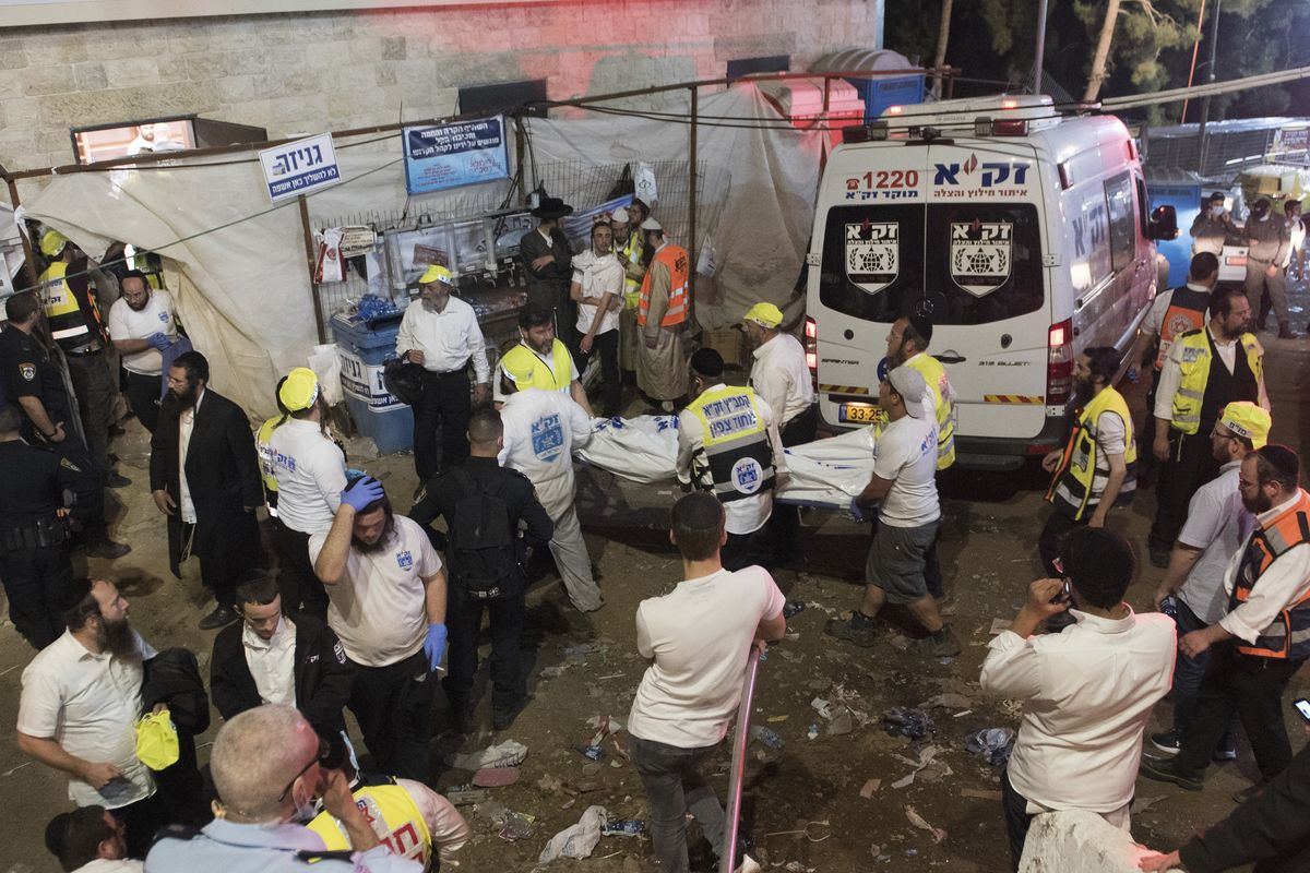 Israeli security officials and rescuers carry a body of a victim who died during a Lag Ba