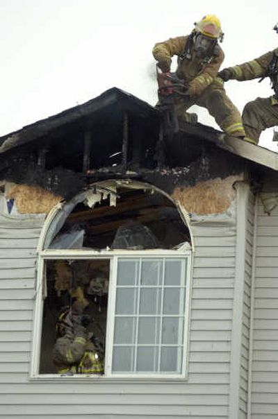 
Spokane firefighters cut debris from a home at 501 W. Auburn Crest Court on Friday after a lightning-caused fire.
 (Christopher Anderson / The Spokesman-Review)