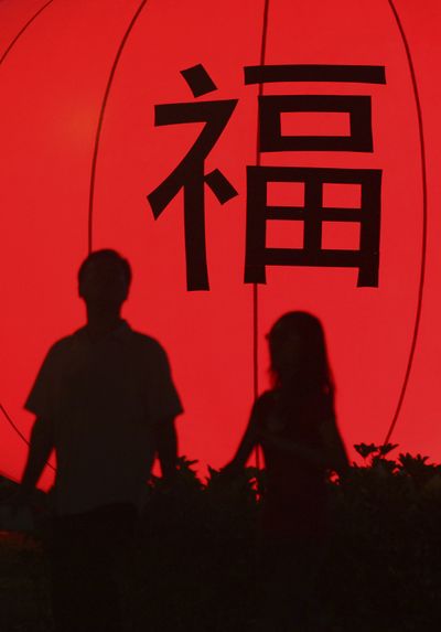 A couple in Singapore  are silhouetted against a lantern. The character translates to “fortune.”  (Associated Press / The Spokesman-Review)