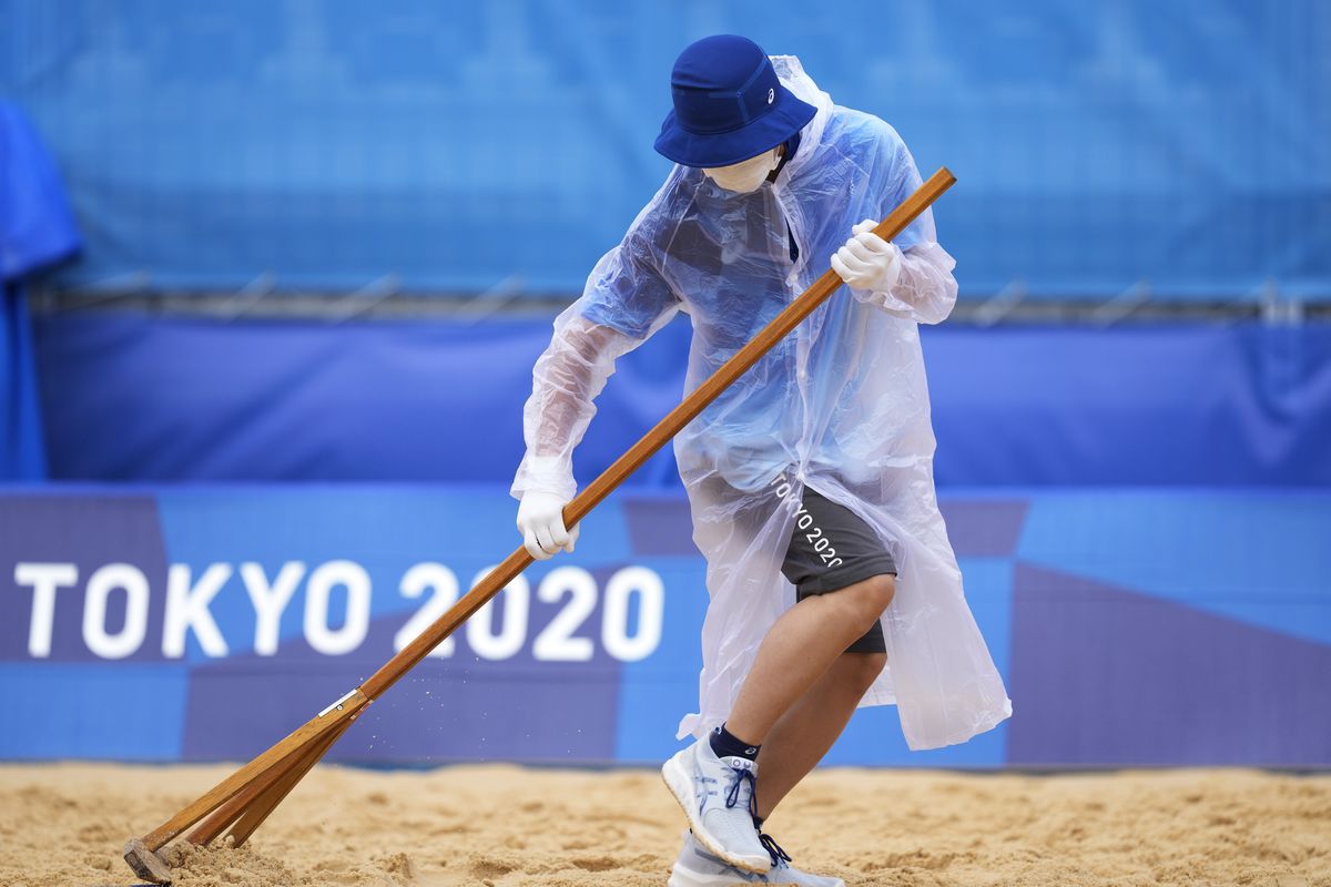 A member of the grounds crew rakes the sand before a men's beach volleyball match at the 2020 Summer Olympics, Tuesday, July 27, 2021, in Tokyo, Japan.  (Petros Giannakouris)