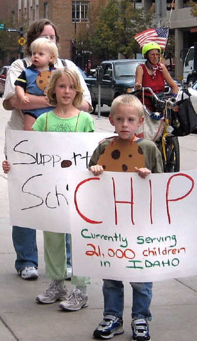 
Dixie Stone, of Boise, holds her son Connor while her daughter, Shauntara, and son Michael hold signs Friday
 (Betsy Russell / The Spokesman-Review)
