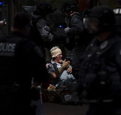 A man checks his phone while surrounded by police and medics after being injured during a civil disturbance in Portland, Ore., on Saturday, June 29, 2019. Competing demonstrations, including members of the so-called Proud Boys and anti-fascist groups, spilled into the streets of downtown Portland, with fights breaking out in places as marchers clashed. (Noble Guyon / AP)