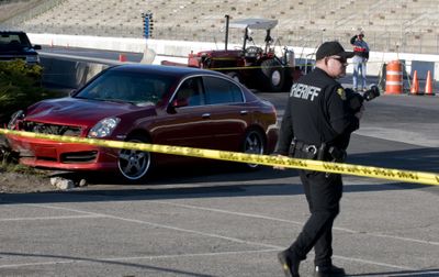 Sheriff’s Deputy Jesse DePriest takes photos of the car that struck and killed a Post Falls man Friday at the Spokane County Raceway.  (Colin Mulvany / The Spokesman-Review)