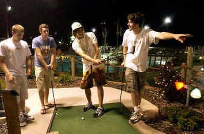 
Post Falls High graduates (from left) Lucas Porter, Trevor Gfeller, Daniel Rowley and Michael Jensen clown around while playing miniature golf at midnight at Triple Play, the site of the all-night post-graduation party Thursday. 
 (Jesse Tinsley / The Spokesman-Review)