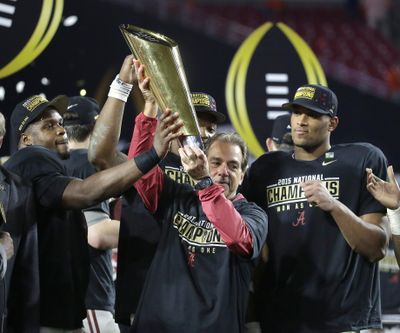 Alabama head coach Nick Saban, center, holds up the championship trophy with players after the NCAA college football playoff championship game against Clemson on Monday in Glendale, Arizona. Alabama won 45-40.