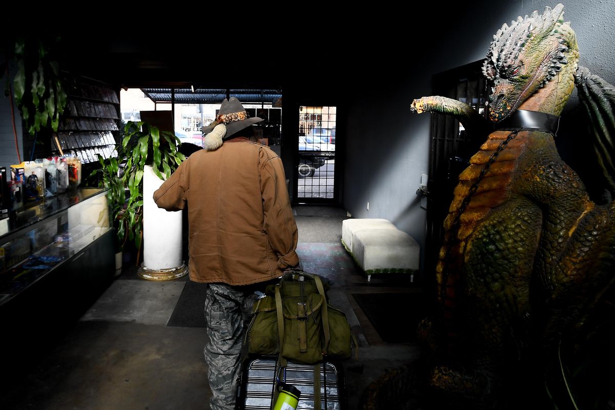 Paul “Conan” Duncan, a homeless  man on Friday, Feb. 14, 2020, rolls his suitcase full of belongings out of Merlyn’s Comics and Games, where he often spends his days in Spokane. (Tyler Tjomsland / The Spokesman-Review)