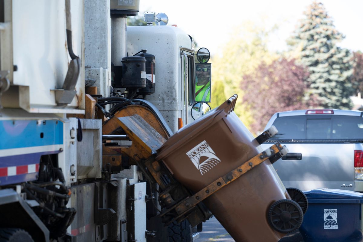 Solid Waste Department driver Rob Lynch watches his mirror as his truck lifts garbage Wednesday in north Spokane.  (Jesse Tinsley/The Spokesman-Revi)