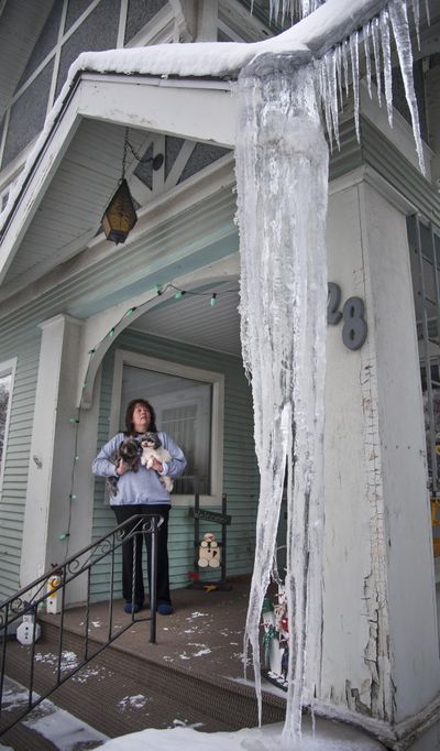 Jill Walter, holding her dogs Boo and Callie, estimates the icicle on her front porch in Spokane’s Corbin Park neighborhood to be more than 8 feet long. Many homes are experiencing an extraordinary amount of ice hanging from roof lines this year. “It’s double (in size) what it normally is,” Walter said. (Dan Pelle / The Spokesman-Review)