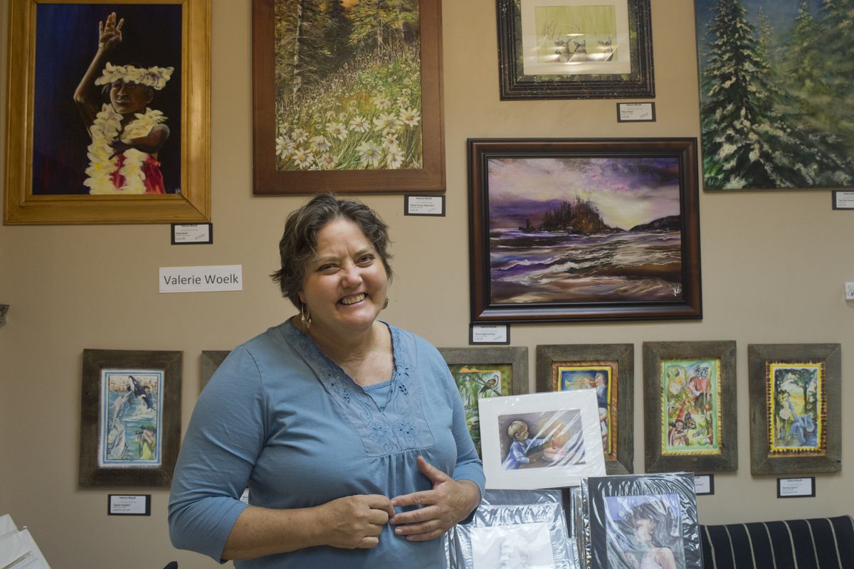 Artist Valerie Woelk stands near her work at the Avenue West Gallery in downtown Spokane on Wednesday. Her work includes landscapes, portraits and abstracts. (Jesse Tinsley)
