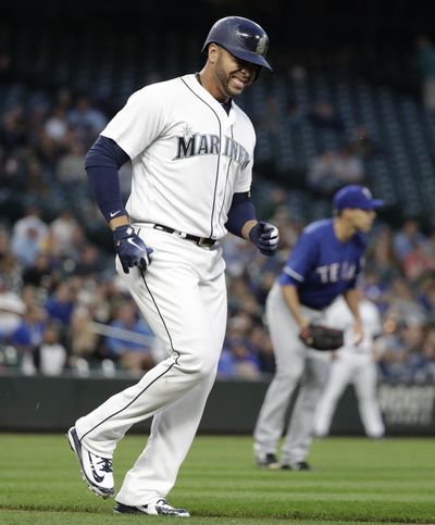 Seattle Mariners' Nelson Cruz, left, limps toward first base after being hit by a pitch from Texas Rangers' Brandon Mann, right, on the foot in a baseball game Tuesday, May 15, 2018, in Seattle. (Elaine Thompson / AP)