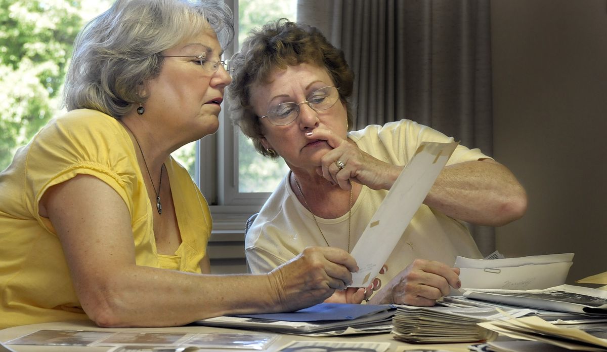 Farol Ann Funk Stroyan, left, and Denise Laos Templeton try to identify classmates from the Marycliff class of 1958 as a photo is passed around during a recent reunion. (Christopher Anderson / The Spokesman-Review)