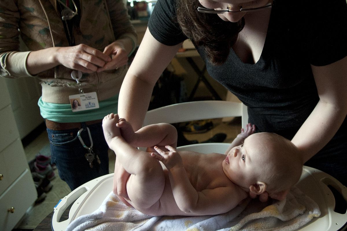 Five-month-old Emma Ohnesorg is placed on a scale by her mother, Holly, in the kitchen of her home in Spokane as she waits to be weighed by Public Health nurse Alison Rasmussen, left on Thursday, April 6, 2017. The visit is part of the Nurse-Family Partnership. (Kathy Plonka / The Spokesman-Review)