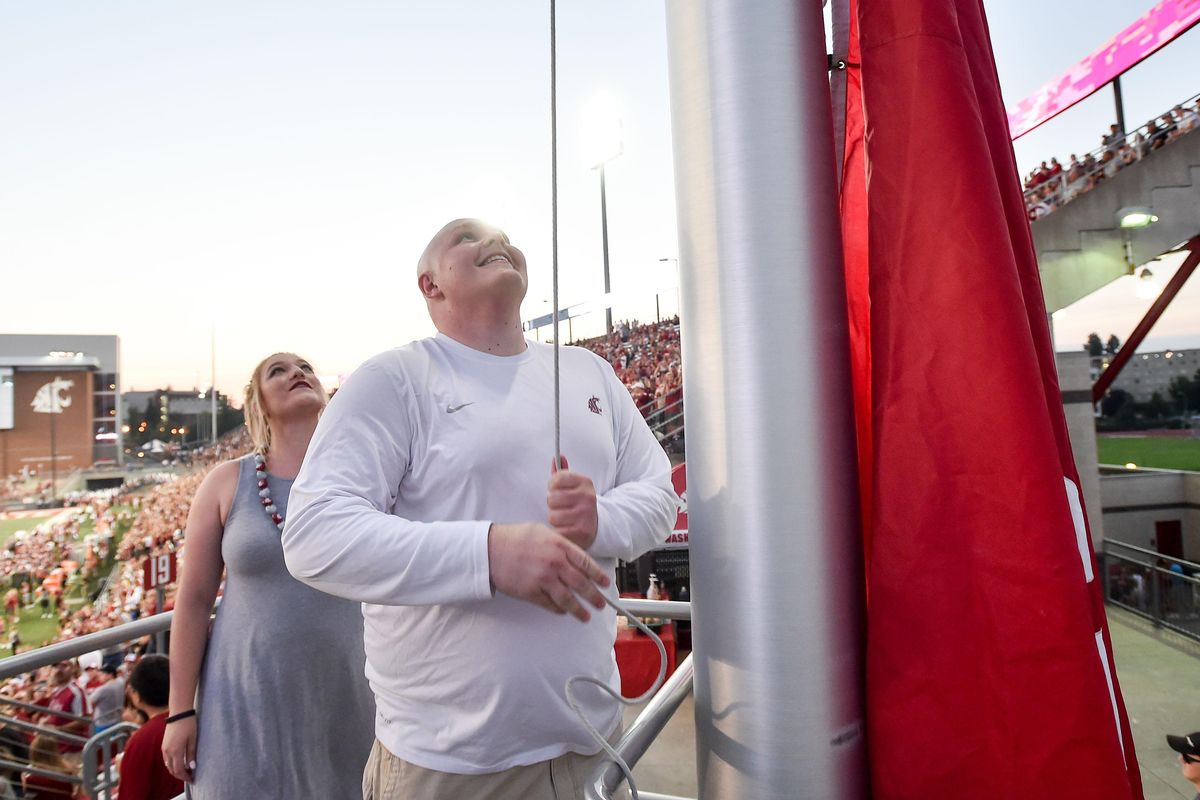 Washington State great Riley Sorenson raises his team's flag as girlfriend Elisabeth Haffner looks before the start of the season opener against Montana State during the first half of a college football game on Saturday, September 2, 2017, at Martin Stadium in Pullman, Wash. (Tyler Tjomsland / The Spokesman-Review)