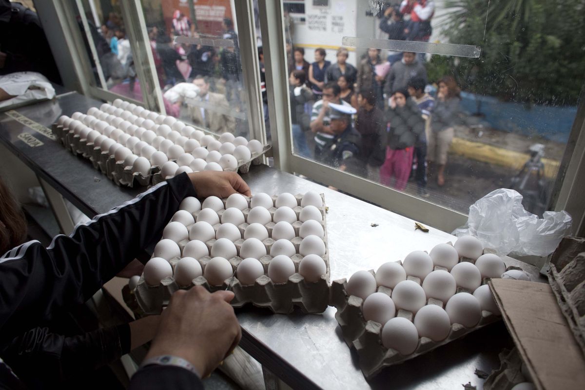 A city worker sells eggs at government subsidized prices as people line up outside the city truck in Mexico City, Friday, Aug. 24, 2012. The Mexican government is battling an egg shortage and hoarding that have caused prices to spike in a country with the highest per-capita egg consumption on earth.  About 11 million chickens were slaughtered after a June outbreak of bird flu. (Alexandre Meneghini / Associated Press)