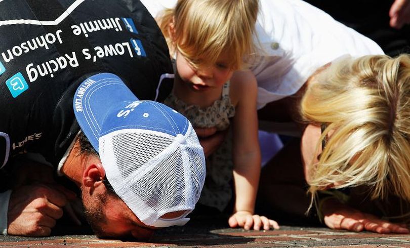 Jimmie Johnson, driver of the #48 Lowe's/Kobalt Tools Chevrolet, kisses the bricks with his daughter Genevieve Marie and wife Chandra after winning the NASCAR Sprint Cup Series Crown Royal presents the Curtiss Shaver 400 at the Brickyard at Indianapolis Motor Speedway on July 29, 2012 in Indianapolis, Indiana. (Photo by Tom Pennington/Getty Images for NASCAR) (Tom Pennington / Getty Images North America)