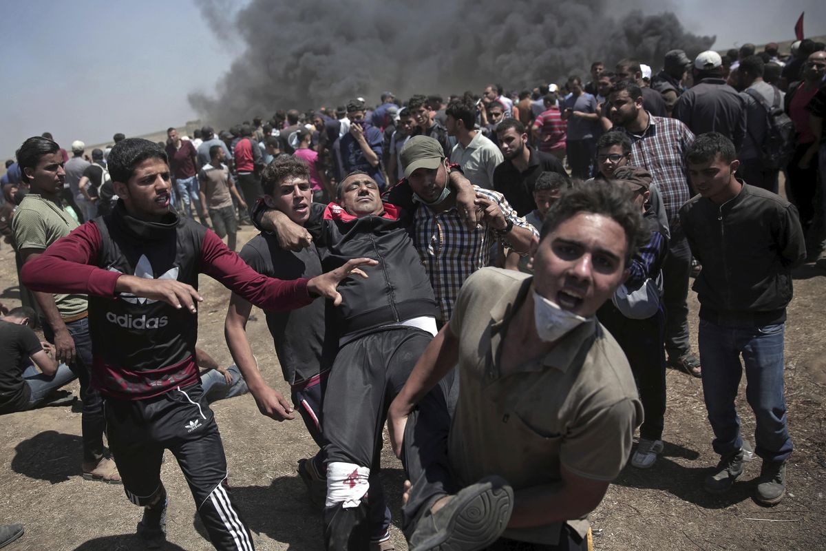 Palestinian protesters carry an injured man who was shot by Israeli troops during a deadly protest at the Gaza Strip
