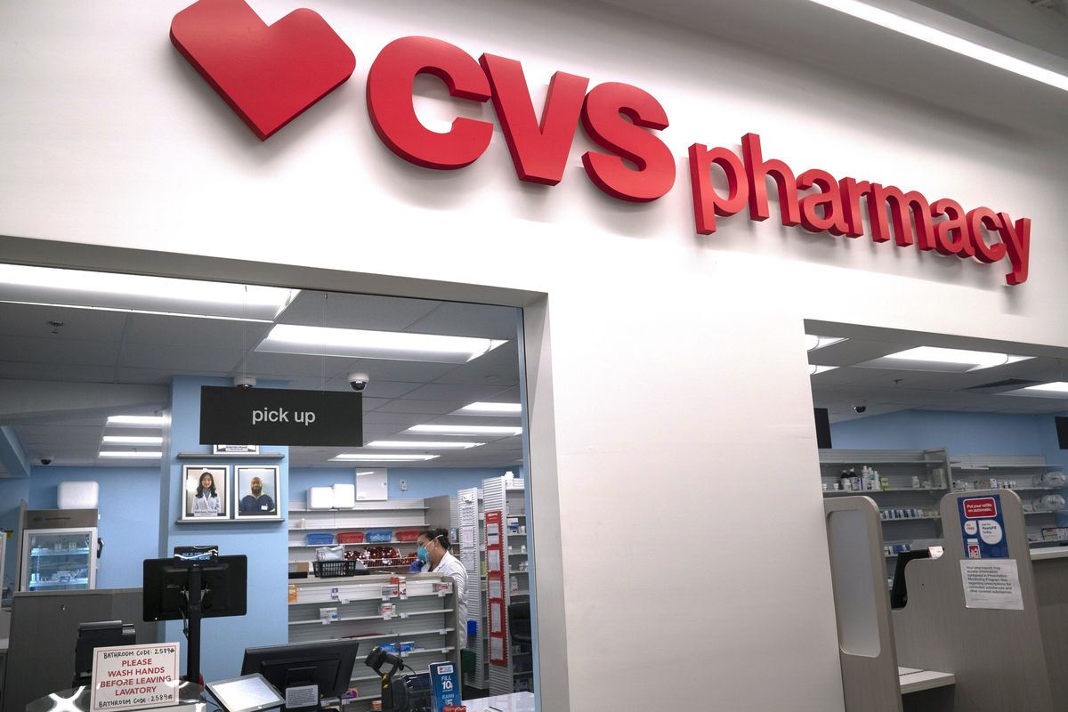 In this March 17, 2020 photo, Pharmacist Evelyn Kim, wears a mask and gloves at the CVS pharmacy at Target in the Tenleytown area of Washington. The Biden administration will begin providing COVID-19 vaccines to U.S. pharmacies, including CVS, part of its plan to ramp up vaccinations as new and potentially more serious virus strains are starting to appear.  (Carolyn Kaster)