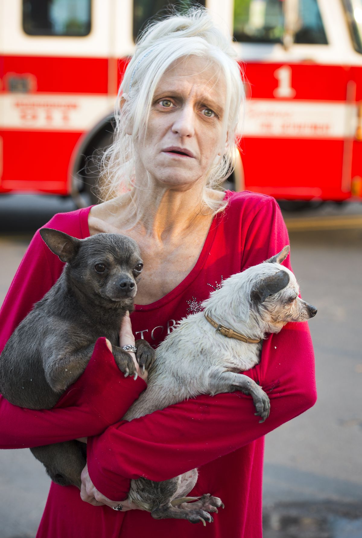 Staring at the burned-out remains of her home, Lisa McCarthy holds her Chihuahuas Theodore, left, and Isis, after they were rescued by Spokane Fire Department firefighters. (Colin Mulvany)