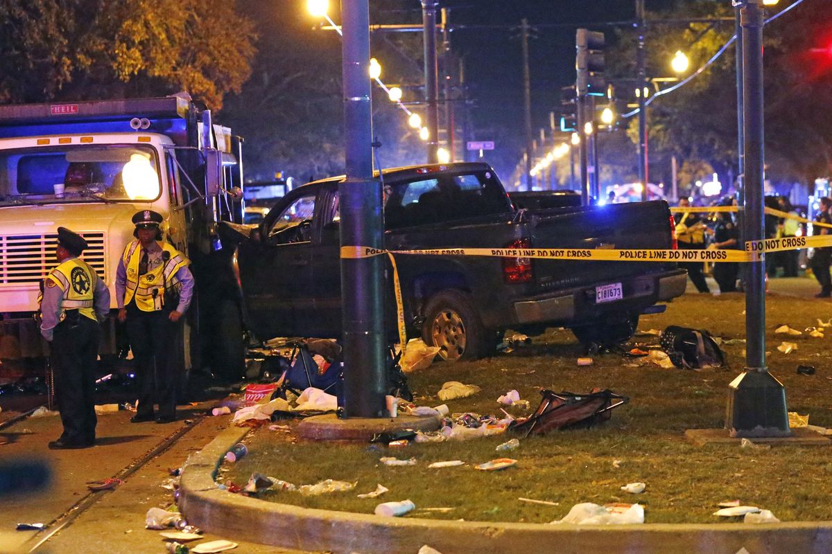 Police stand next to a pickup truck that slammed into a crowd and other vehicles, causing multiple injuries, coming to a stop against a dump truck, during the Krewe of Endymion parade in New Orleans, Saturday. (Gerald Herbert / Associated Press)