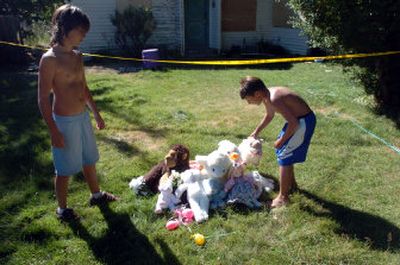 
Phoenix Daley watches Faustino Anaya straighten up the makeshift memorial for Kylla Pahl on Thursday. Kylla died in a fire in the small house behind them.
 (Jesse Tinsley / The Spokesman-Review)