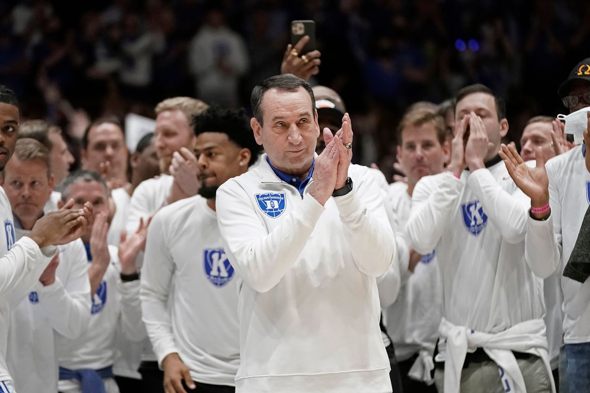 Surrounded by former players, Duke coach Mike Krzyzewski applauds while being recognized prior to the team