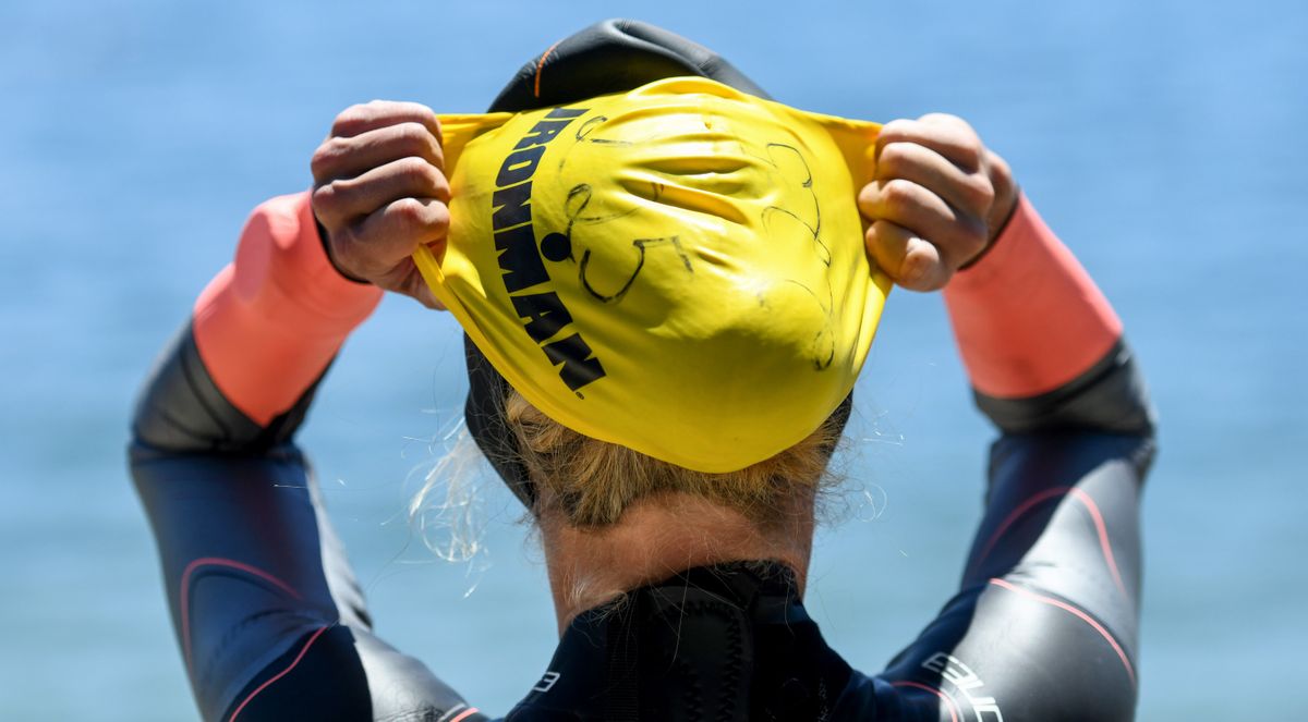 Ironman competitor Rachael Tatko of Boise pulls her swim cap as she prepares to swim in Coeurd’Alene Lake on Thursday, June 23, 2022 in preparation for Ironman 70.3 on Sunday.  (Kathy Plonka/The Spokesman-Review)