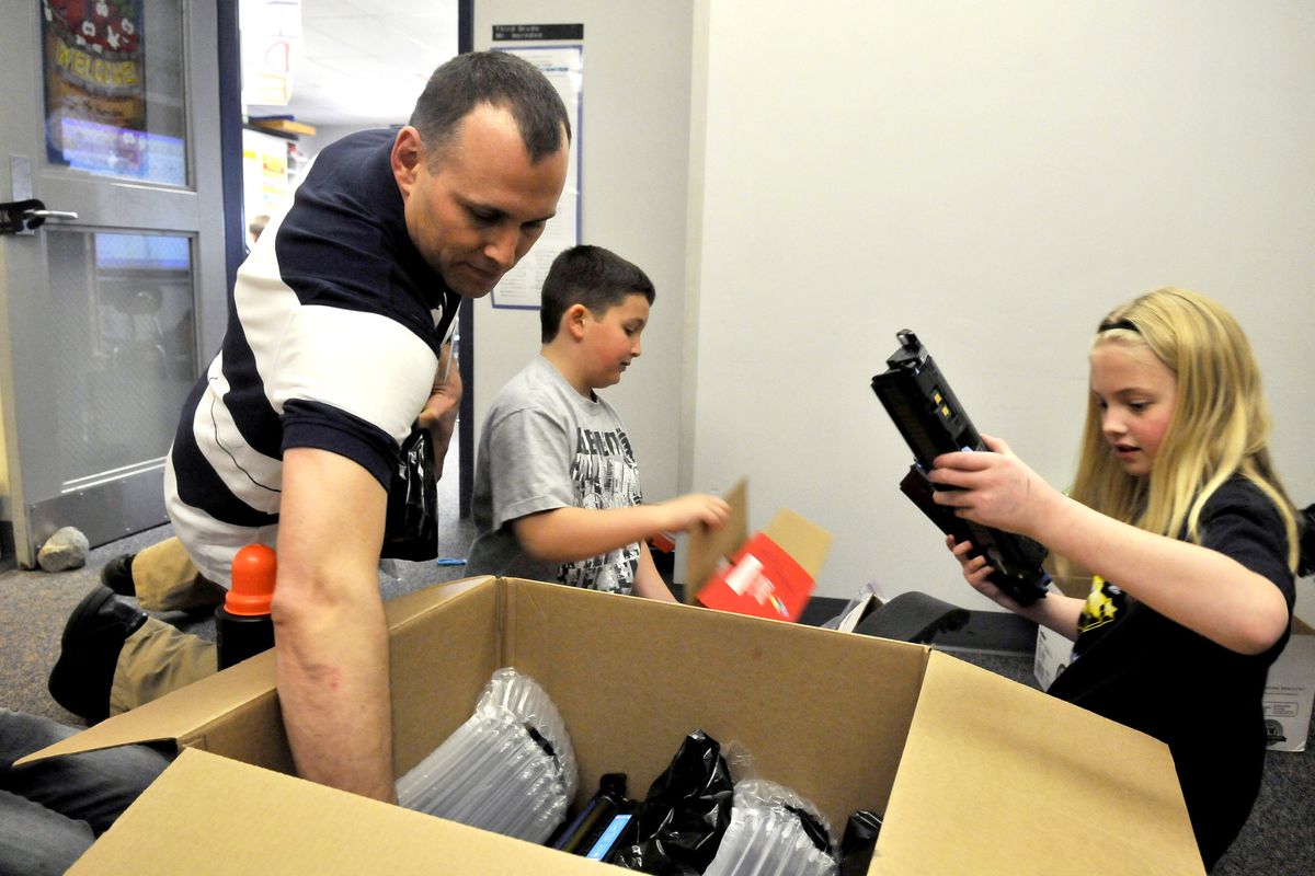 At Broadway Elementary, teacher Darren Herndon, left, and students Adam Sabota, center, and Destanee Wilson pack a box with empty printer cartridges to be recycled. Herndon has run the school