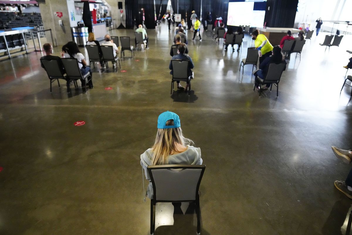 FILE - In this March 25, 2021, file photo, people wait to receive a vaccine at Mercedes-Benz Stadium in Atlanta. A new poll from The Associated Press-NORC Center for Public Affairs Research shows that the percentage of Americans resisting getting inoculated has shrunk in the past few months. But it’s still not enough to pull America out of the pandemic, and reach herd immunity.  (Brynn Anderson)