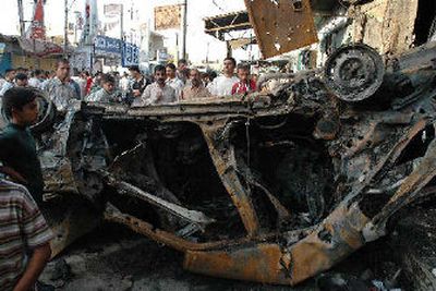 
Iraqis stand around a destroyed vehicle Friday at the site of Thursday night's suicide bombings in Balad, Iraq. Three suicide attackers exploded car bombs in the heart of a bustling, mainly Shiite town, killing at least 102 people.
 (Associated Press / The Spokesman-Review)