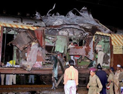 
People stand near a train carriage that was destroyed in a bomb blast Tuesday in Bombay, India. Eight explosions along the railway line killed 190 people and injured 625. 
 (Associated Press photos / The Spokesman-Review)