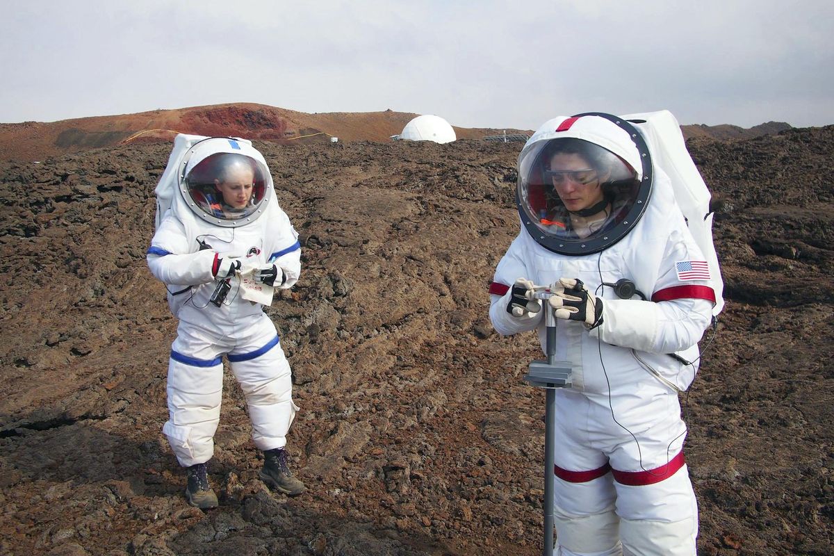 In this May 23, 2014, photo provided by the University of Hawaii, Lucie Poulet, right, uses a geotechnical tool while Annie Caraccio records the data during a previous study outside the domed structure that will house six researchers for eight months in an environment meant to simulate an expedition to Mars, on Mauna Loa on the Big Island of Hawaii. (Ross Lockwood / Associated Press)