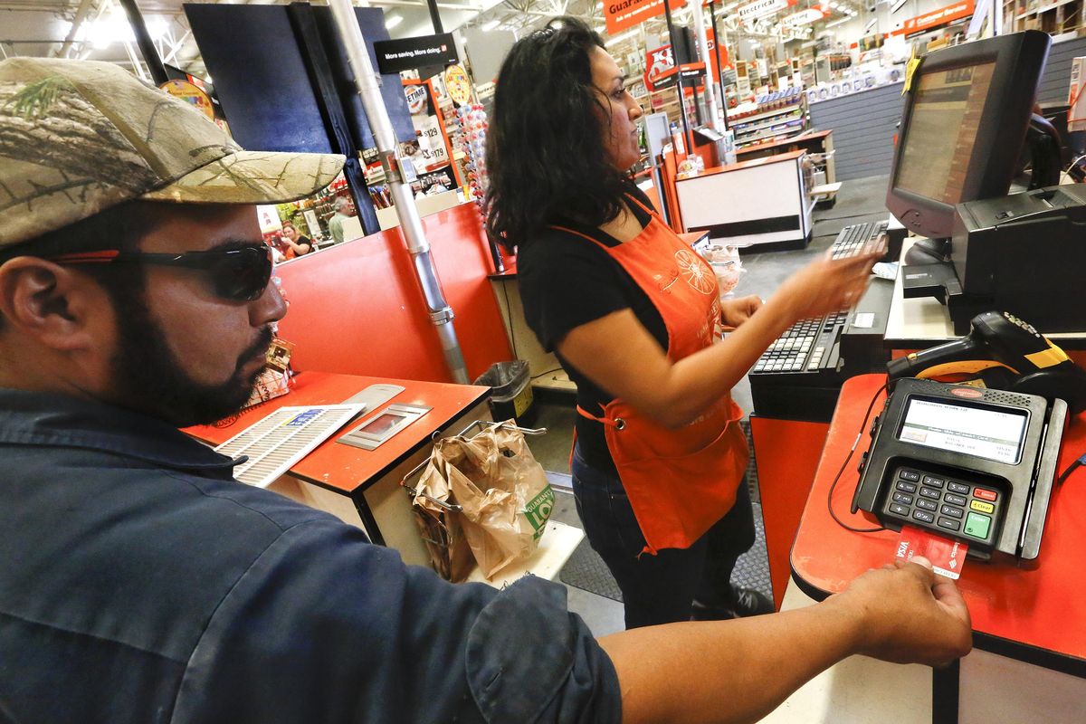 Robert Montanez, 39, left, inserts his debit card, equipped with an EMV chip, into an EMV reader while making a purchase at a Home Depot store in Burbank, Calif., on Sept. 23, 2015. (Mel Melcon / Mel Melcon/Los Angeles Times)