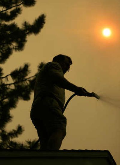 
Owner Evan Williams sprays down the roof of Evan's American Gourmet restaurant in South Lake Tahoe on Tuesday.Associated Press photos
 (Associated Press photos / The Spokesman-Review)