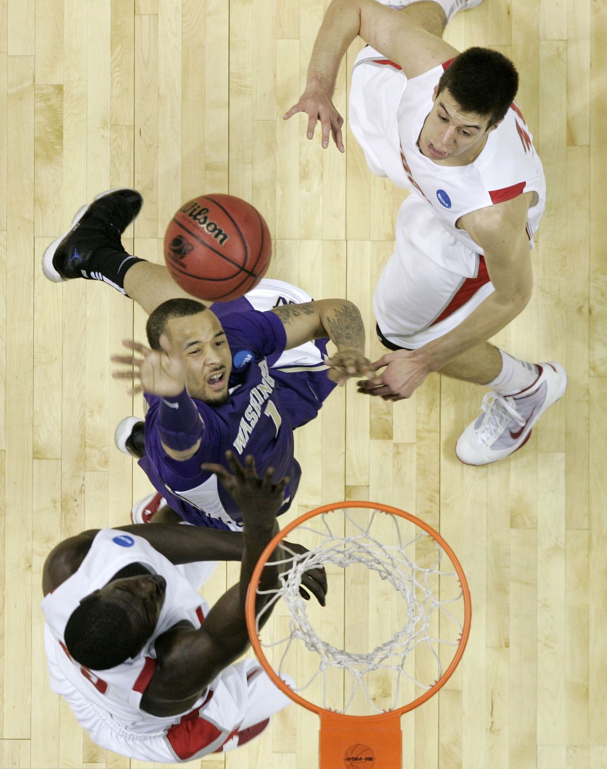Washington’s Venoy Overton shoots against New Mexico’s Will Brown, left, and Roman Martinez.  (Associated Press)