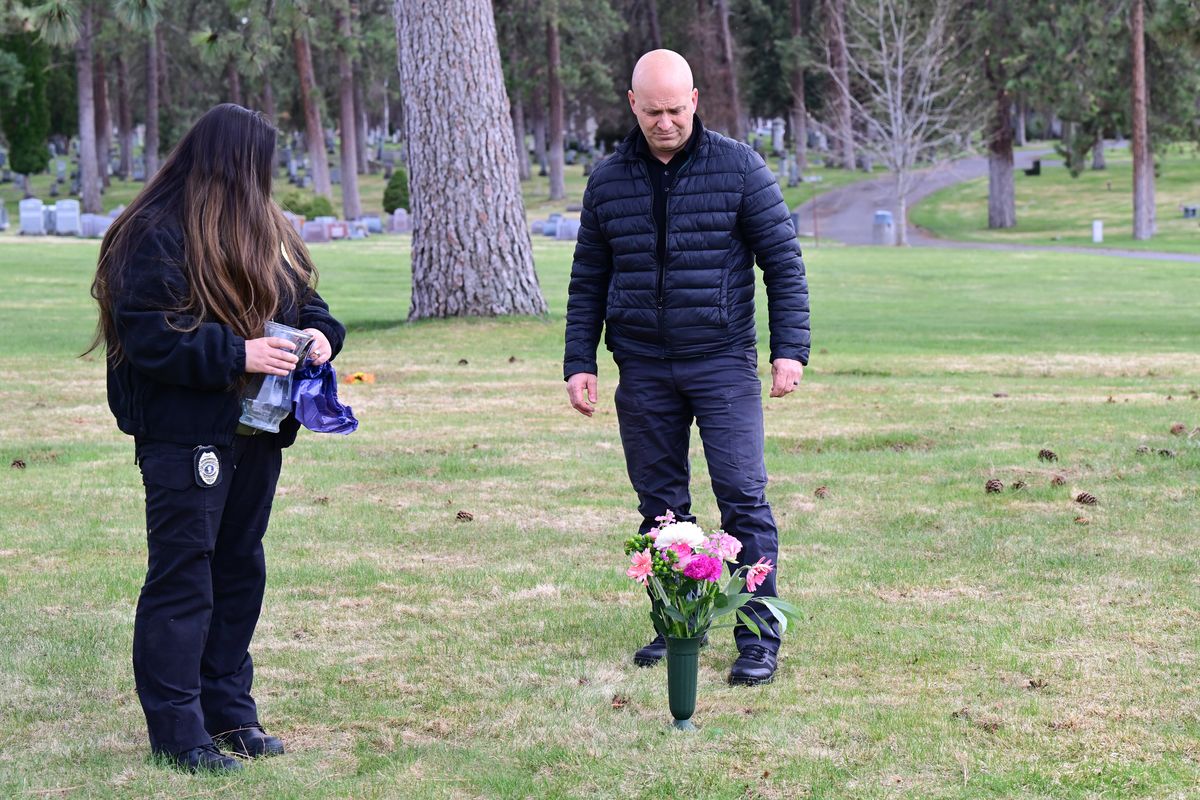 Spokane police Sgt. Zac Storment and Deputy Medicolegal Death Investigator Nicole Hamada stand for a moment on Friday after laying flowers on the unmarked grave of Ruth Belle Waymire at Fairmount Memorial Park in Spokane. For 40 years, officials struggled to identify her, dubbing her “Millie,” and burying her in Fairmount Memorial Park under that name.  (Tyler Tjomsland/The Spokesman-Review)