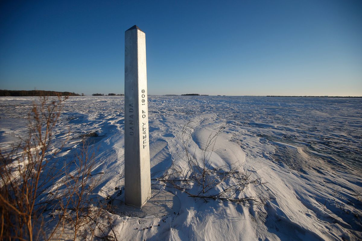 A border marker, between the United States and Canada is shown just outside of Emerson, Manitoba, on Thursday, Jan. 20, 2022. A Florida man was charged Thursday with human smuggling after the bodies of four people, including a baby and a teen, were found in Canada near the U.S. border, in what authorities believe was a failed crossing attempt during a freezing blizzard. The bodies were found Wednesday in the province of Manitoba just meters (yards) from the U.S. border near the community of Emerson.  (JOHN WOODS)