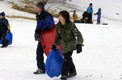 
Kyle Harding, 15, left, and Michael Salcido, 12, start hiking up the sledding hill at Valley Mission Park in Spokane Valley on Sunday. Sledders have come out in droves since the recent snowfall in the area. Some sledders created jumps on the hill.
 (Liz Kishimoto / The Spokesman-Review)