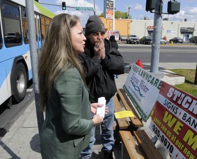 Mayor Mary Verner holds a press conference at the corner of Indiana Avenue and Monroe Street on Monday to announce that bus benches with signs will be removed. Bus rider Dave Parisia, right, told her removing the benches would be a “waste of money.”  (Dan Pelle / The Spokesman-Review)