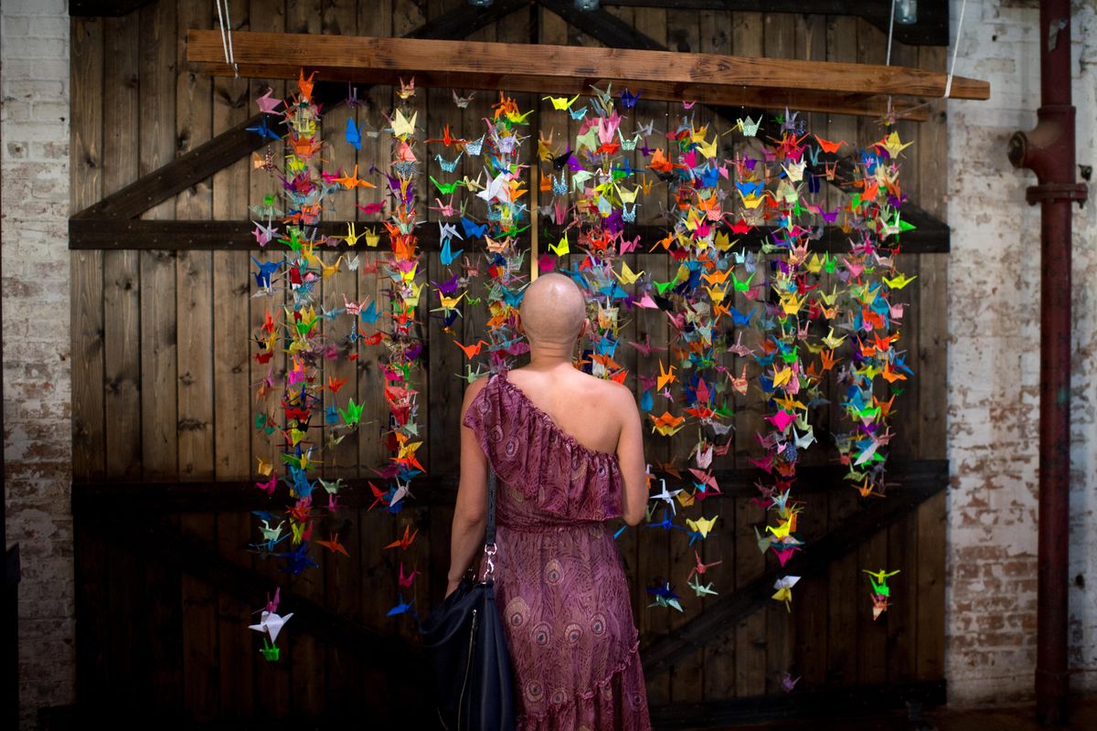 Mandi Anderson takes in the sight of strings of origami cranes her Lantern Tap House co-workers, customers and friends folded in her honor after she was diagnosed with stage 4 breast cancer earlier this year on Thursday, July 20, 2017, at the Cracker Building in Spokane, Wash. The group folded over a thousand cranes - some pictured here - and held a benefit concert in her honor. They also set up a fundraising site for her: www.youcaring.com/mandianderson. (Tyler Tjomsland / The Spokesman-Review)