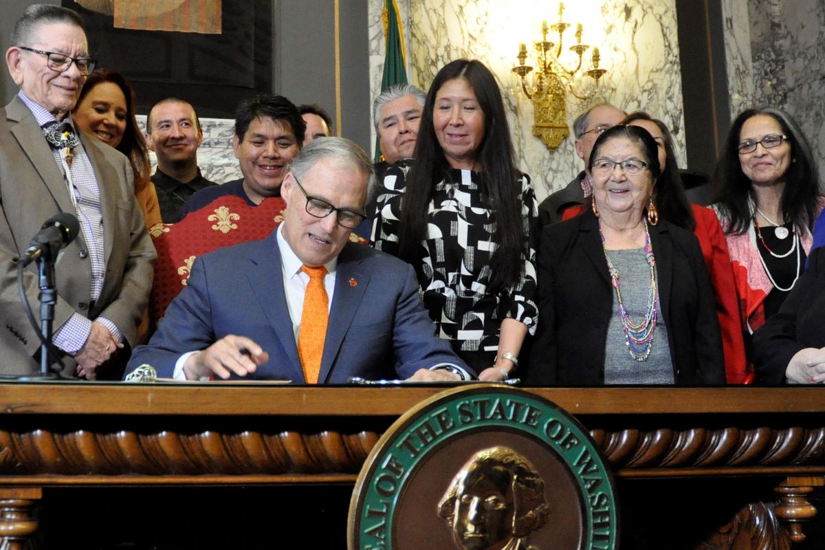 OLYMPIA – Gov. Jay Inslee, flanked by Sen. John McCoy and Rep. Debra Lekanoff, the state’s two Native American legislators, signs the Native American Voting Rights Act Thursday. (Jim Camden / The Spokesman-Review)