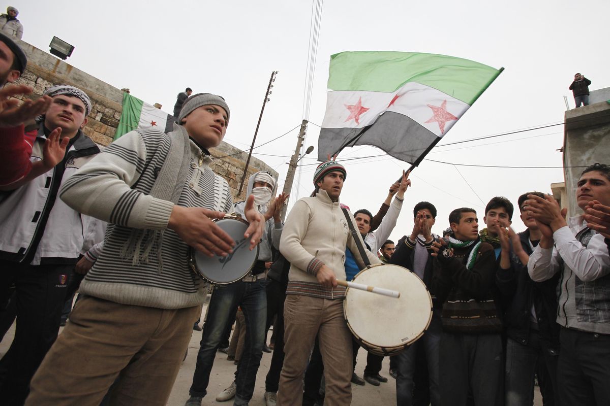Anti-Syrian regime protesters play drums and wave a revolutionary flag during a demonstration in Idlib, Syria, on Monday. (Associated Press)
