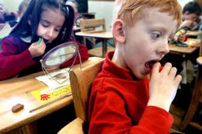
First-graders Logan Sorensen, right, and Kayla Thompson use plastic-handled flossers to clean between their teeth during a class session with Dr. Rich Bailey, a Moscow dentist. 
 (Jesse Tinsley / The Spokesman-Review)