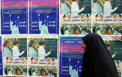 
An Iraqi woman passes election campaign posters in Baghdad, Iraq, on Saturday. The commission organizing elections extended the deadline for filing candidates' lists for five days after several parties requested more time to prepare their slates. 
 (Associated Press / The Spokesman-Review)