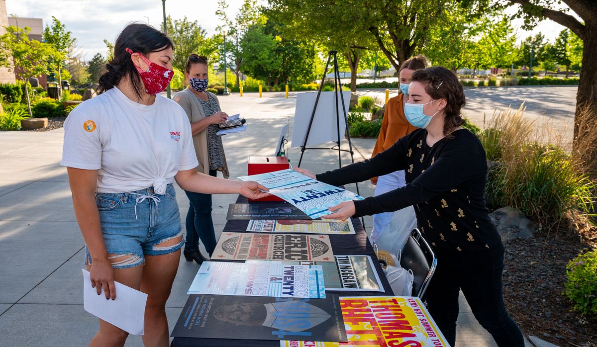 During a Happy Hour Vaccine Clinic at Spokane Arena last month, newly vaccinated Rachel Ryan, 21, left, receives a free concert poster from Spokane Arena employee Holly Williams.   (COLIN MULVANY/THE SPOKESMAN-REVIEW)