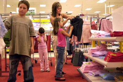 
Kayla MacCary, 7, checks out a denim blazer with her mom, April, at Target in Spokane Valley this week. Her brother, Devin, 12, and sister, Madison, 6, wait their turn . 
 (Liz Kishimoto / The Spokesman-Review)