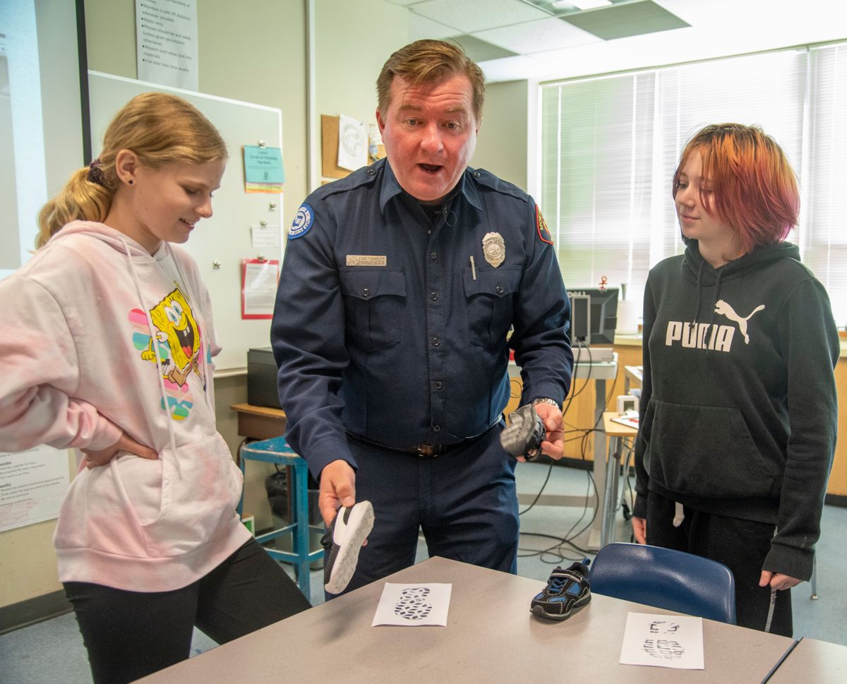Spokane firefighter and fire investigator Rick Freier, center, talks with "investigators" Millie Hutchins, left, and Axel Cannon, 13, right, about identifying foot prints in a class of middleschoolers at Centennial Middle School Wednesday, June 1, 2022 in Spokane Valley, Washington. Freier has developed and taught a class for middleschool students that combines fire science, fire safety and fire investigation.  (Jesse Tinsley/The Spokesman-Review)