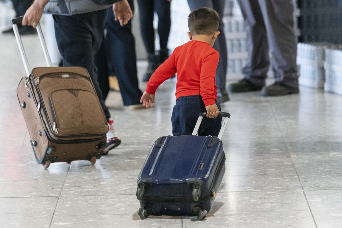 A young boy pulls a suitcase as refugees arrive from Afghanistan aboard an evacuation flight at Heathrow Airport in London, Thursday Aug. 26, 2021. The U.K. defense ministry has organised an air-lift of vulnerable citizens from Kabul, following the Taliban assuming power in Afghanistan.  (Dominic Lipinski)