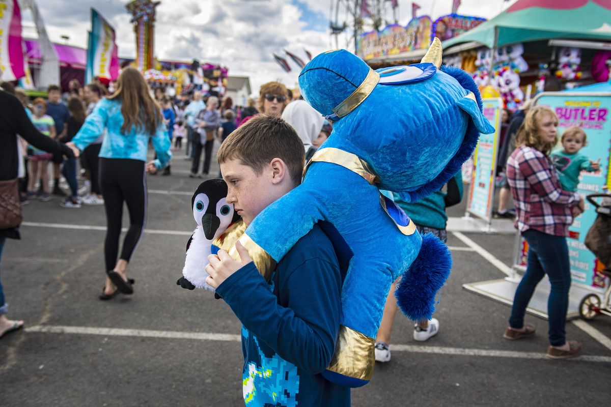 On the last day of the Spokane County Interstate Fair, Marek Hill, 9, walks the carnival midway with his winnings--a stuffed unicorn and penguin, Sunday, Sept. 16, 2018. (Colin Mulvany / The Spokesman-Review)