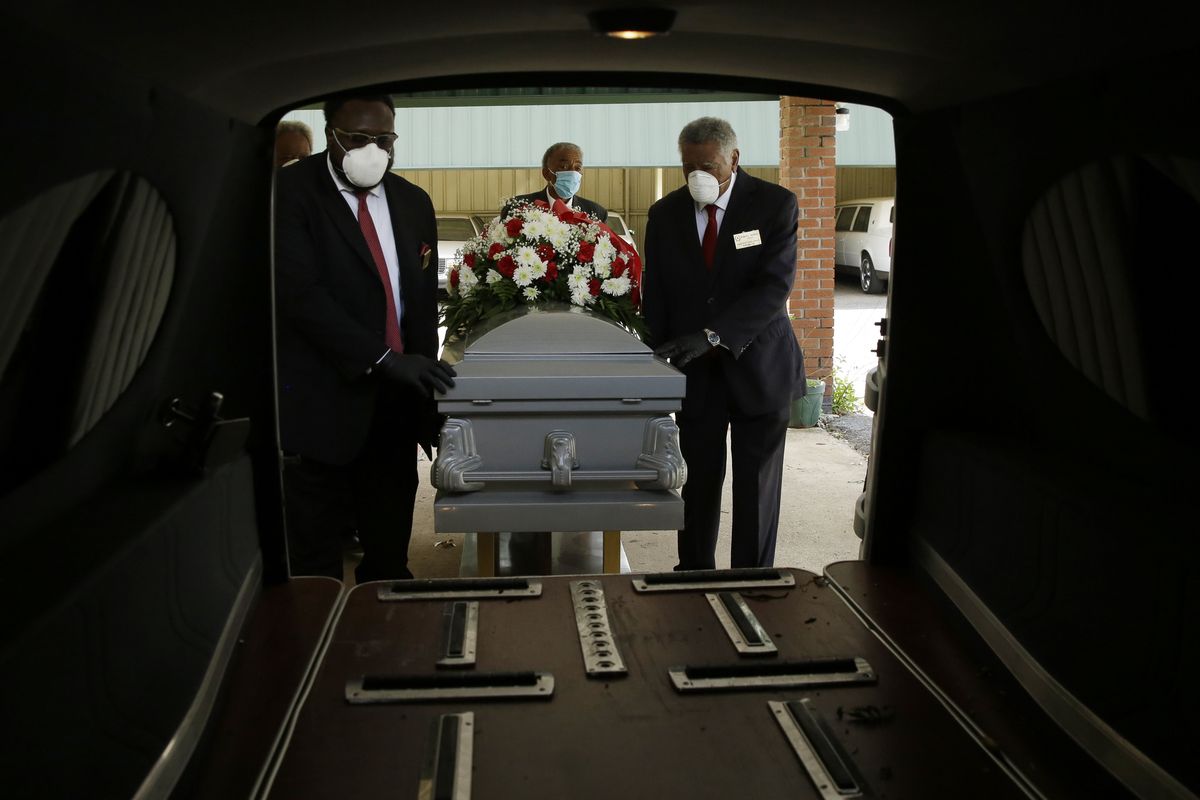 In this Saturday, April 18, 2020 photo, mortician Cordarial O. Holloway, foreground left, funeral director Robert L. Albritten, foreground right, place a casket into a hearse in Dawson, Ga. In a Feb. 25-March 1, 2021 poll conducted by The Associated Press-NORC Center for Public Affairs Research, about 1 in 5 Americans say they lost a relative or close friend to the coronavirus.  (Brynn Anderson)