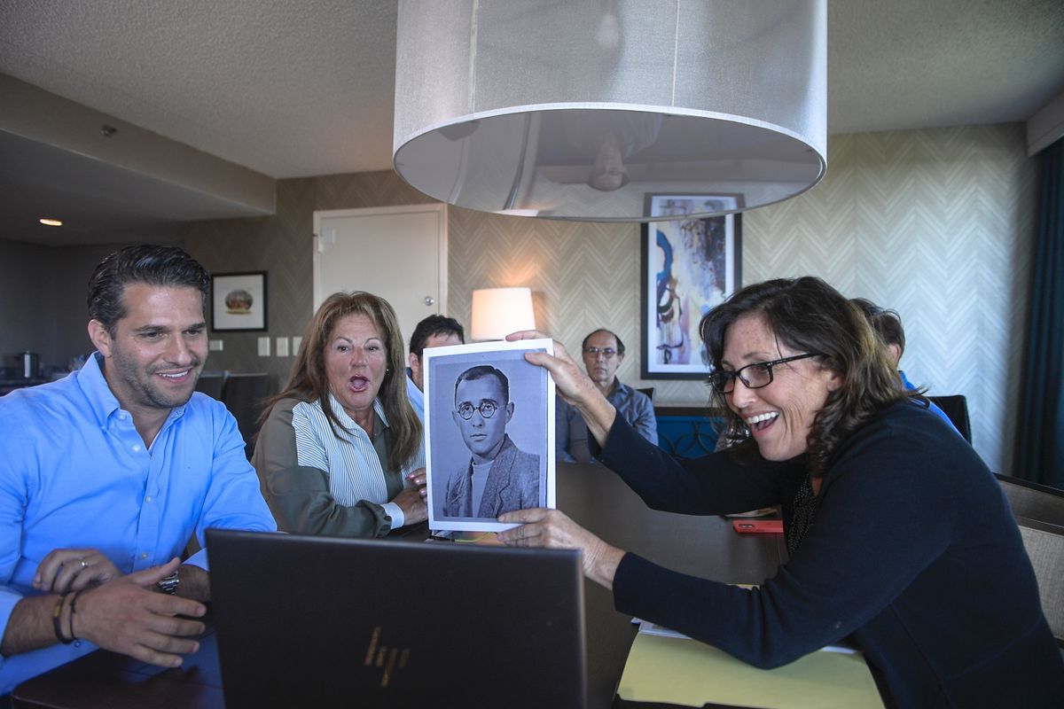 Anna Salton Eisen holds up a photo of Emil Ringel, father of Barbara Ringel, for a Zoom video call during a gathering for families of Holocaust survivors in East Brunswick, N.J., on Sunday, Sept. 26, 2021. Seventy-six years after American soldiers cut down the barbed wire and fulfilled the prisoners’ impossible dream of freedom, Eisen brought together survivors’ loved ones.  (Brittainy Newman)